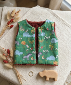 Gilet de berger réversible pour bébé avec motif animaux de la savane et intérieur moumoute terracotta.