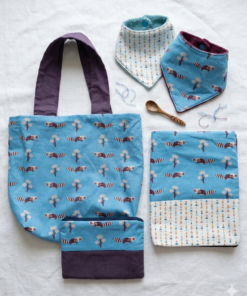 Coffret cadeau bébé artisanal : accessoires textiles assortis en coton bleu avec motifs ratons laveurs et formes géométriques.